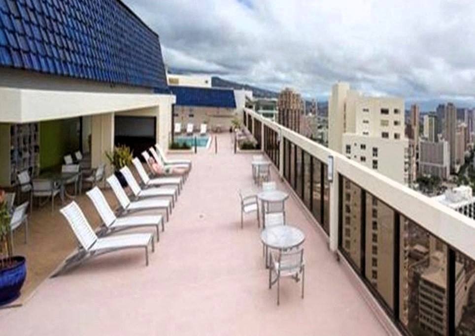 A balcony with chairs and tables overlooking a cityscape.